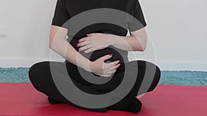 A pregnant girl is doing yoga meditation. The baby in the tummy pushes. A woman stroking her belly