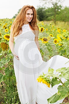 Pregnant girl in the field with sunflowers