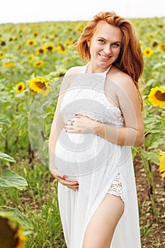 Pregnant girl in the field with sunflowers