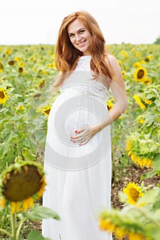 Pregnant girl in the field with sunflowers