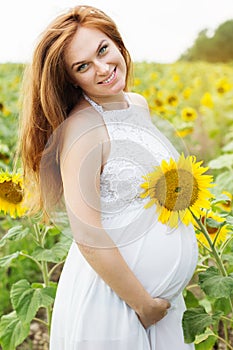 Pregnant girl in the field with sunflowers