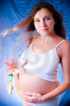 Pregnant girl with a flower. A pregnant woman with a lily. Pregnant woman holding her belly itself