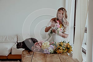 Pregnant girl with flowers and a cat in a light dress