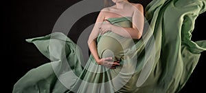 Pregnant girl in flowing and flying fabric on a black background