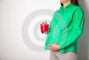 A pregnant girl in a green blouse holds a red cactus pot. Coznept of cutting pains and colic in the abdomen in pregnant