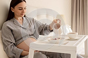 A pregnant girl is having breakfast in bed