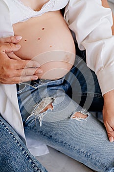 Pregnant girl and her companion hold hands. the expectation of the child