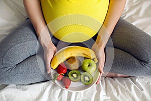 Pregnant girl holding a bowl of fruit