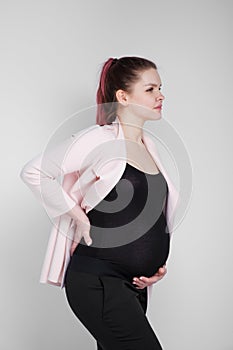 Pregnant girl holding on to her back. Pain, heaviness in the back.