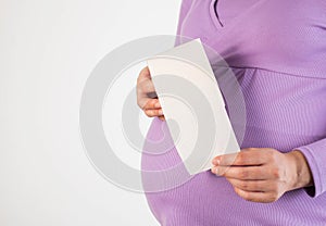 Pregnant girl holding toilet paper on the background of her belly. The concept of indigestion in pregnant women, bloating. Copy