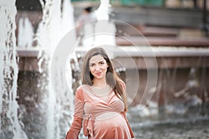 Pregnant girl near the fountain. happy and carefree pregnancy