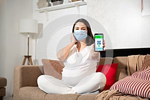 A pregnant girl in a protective face mask shows a vaccination certificate on her phone.