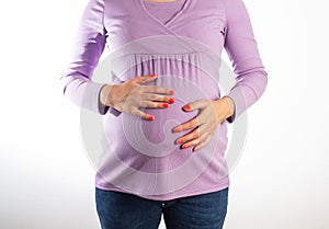 A pregnant girl with a purple sweater holds her swollen belly. Concept of digestive problems in pregnant women
