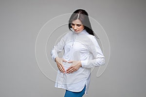 Pregnant girl show heart shape gesture on belly waiting for baby. Maternity concept. Expectant mother during pregnancy