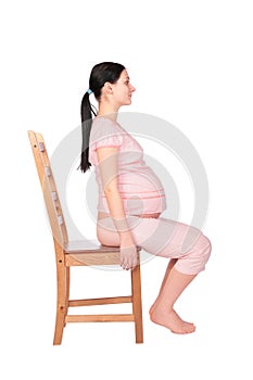 Pregnant girl sits on chair sideview photo