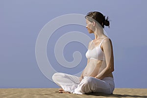 Pregnant girl sitting on the sand