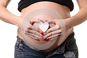 Pregnant girl with small heart symbol. Close up. White background