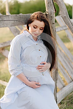 Pregnant girl in summer outdoors in the setting sun