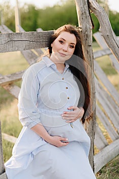 Pregnant girl in summer outdoors in the setting sun