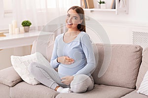 Pregnant Girl Touching Belly Smiling Sitting On Couch At Home