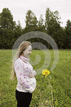 Pregnant girl walking in nature and smiling