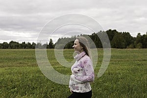 Pregnant girl walking in nature and smiling