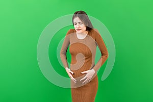 a pregnant girl who has a stomach ache stands on a colored background. 