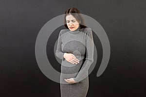 a pregnant girl who has a stomach ache stands on a colored background. 