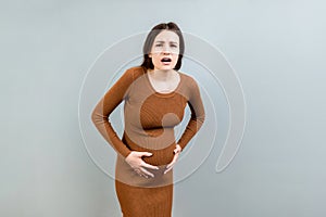 A pregnant girl who has a stomach ache stands on a colored background. isolated