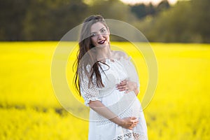 Pregnant girl on a yellow background. looks at his stomach, imagines his unborn child. Maternity concept