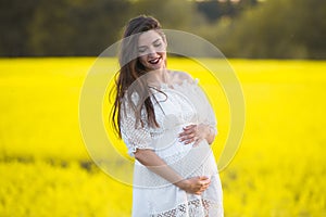 Pregnant girl on a yellow background. looks at his stomach, imagines his unborn child. Maternity concept