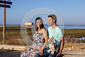 Pregnant happy couple with small dog