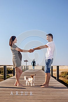 Pregnant happy couple with small dog