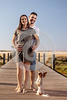 Pregnant happy couple with small dog