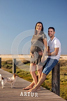 Pregnant happy couple with small dog