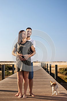 Pregnant happy couple with small dog