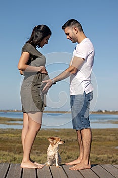 Pregnant happy couple with small dog