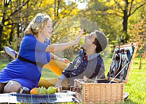 Pregnant happy and smiling couple on picnic with cat