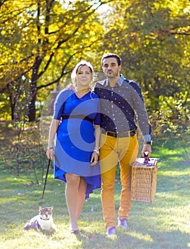 Pregnant happy and smiling couple on picnic with cat