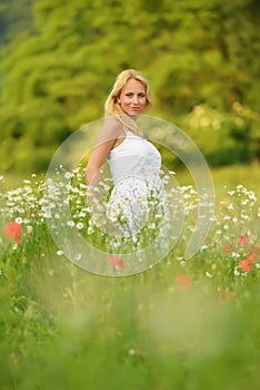 Pregnant happy woman in a flowering poppy field outdoors