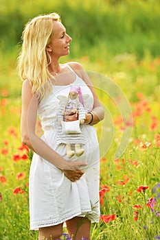 Pregnant happy woman in a flowering poppy field outdoors