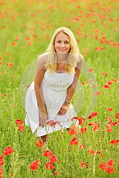 Pregnant happy woman in a flowering poppy field outdoors