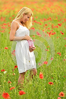 Pregnant happy woman in a flowering poppy field outdoors