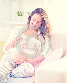 Pregnant happy woman holding baby shoes