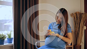 Pregnant happy woman holding baby shoes in her hands. Mom expecting her baby. Pregnant woman belly. Pregnancy. Maternity concept.