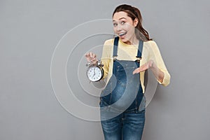 Pregnant happy woman holding clock