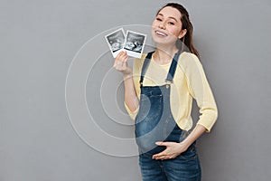 Pregnant happy woman holding ultrasound scans