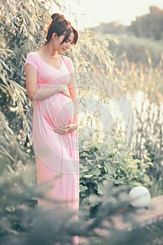 Pregnant happy Woman touching her belly. Full length Pregnant beauty young mother outdoor portrait, caressing her belly