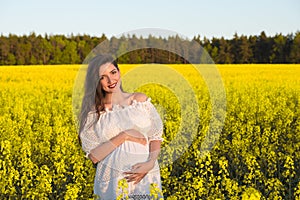 Pregnant happy woman touching her belly. Pregnant middle-aged mother portrait caressing her belly and smiling close-up. Healthy