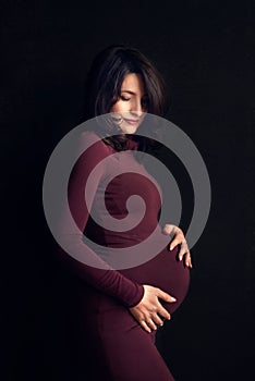 Pregnant happy Woman touching her belly. Pregnant middle aged mother portrait, caressing her belly and smiling close-up. Healthy P